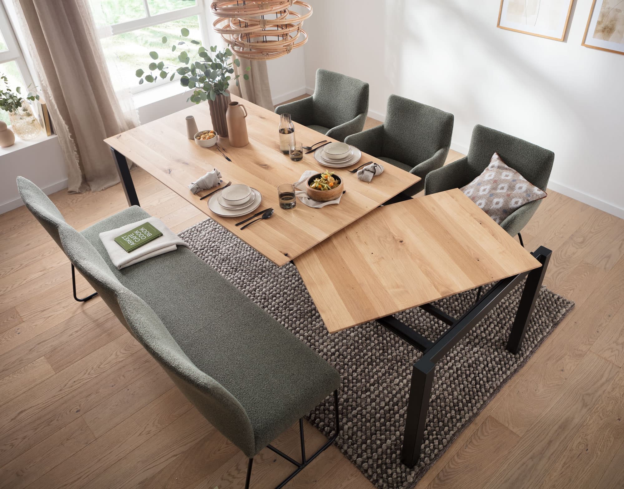Moderner Essbereich mit einem Holz-Tisch, vier grünen Stühlen und einer Bank, dekoriert mit Geschirr und einem Teppich.