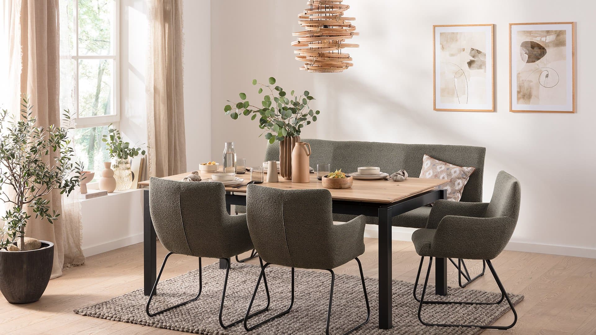 Moderne Esszimmer mit einem Holztisch, grünen Stühlen, einer Pflanzenanordnung und Holzdeko über dem Tisch.