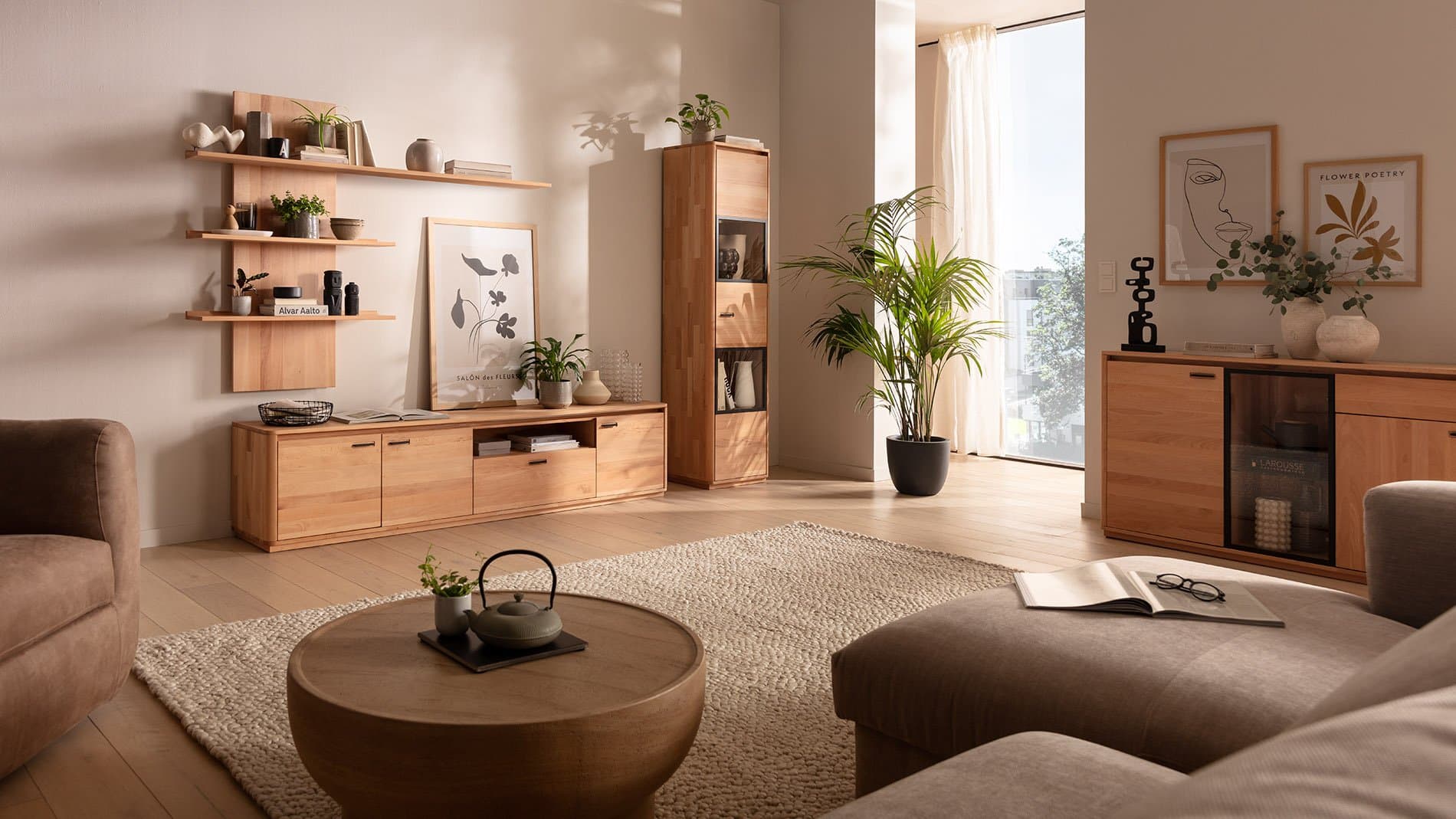 Heller Wohnraum mit modernen Möbeln aus Holz, einem runden Tisch und Pflanzen, große Fenster sorgen für viel Tageslicht.
