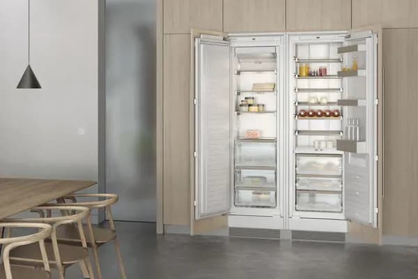 Moderne Küche mit einem offenen, weißen Kühlschrank, der gefüllt ist. Ein Esstisch mit Stühlen im Vordergrund.