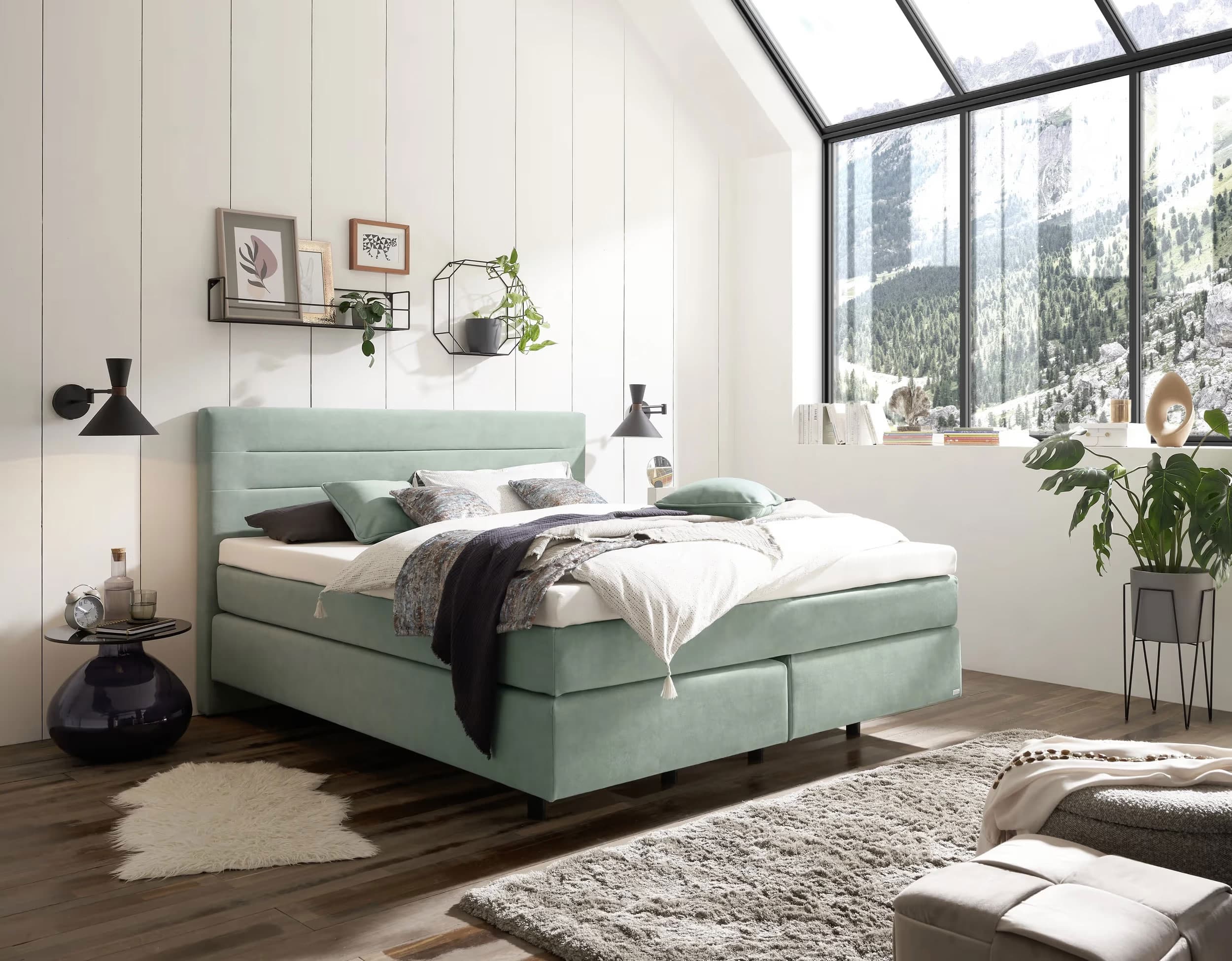 Gemütliches Schlafzimmer mit einem mintgrünen Doppelbett, großen Fenstern und modernen Dekorationselementen.