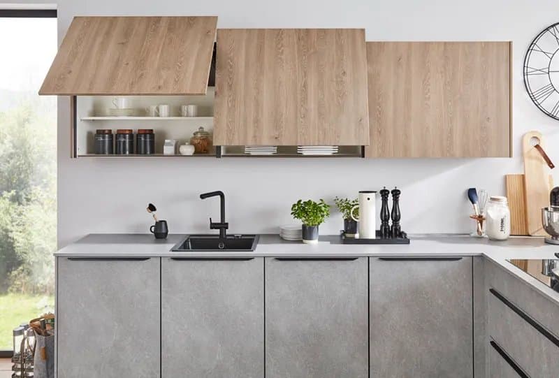 Moderne Küchenzeile mit grauen Schränken, Holzfronten und einem Spülbecken, dekoriert mit Kräutern und Küchengeräten.