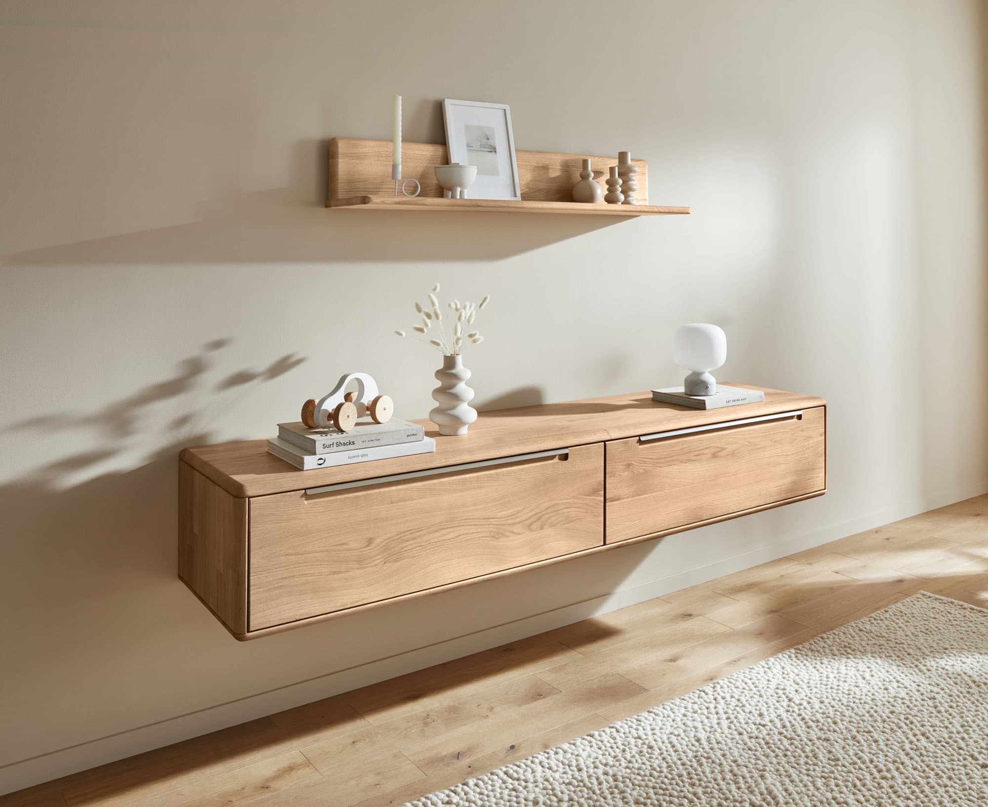 Holzregal und -schrank an der Wand, dekoriert mit verschiedenen Accessoires und einer Lampe, in einem hellen Raum.