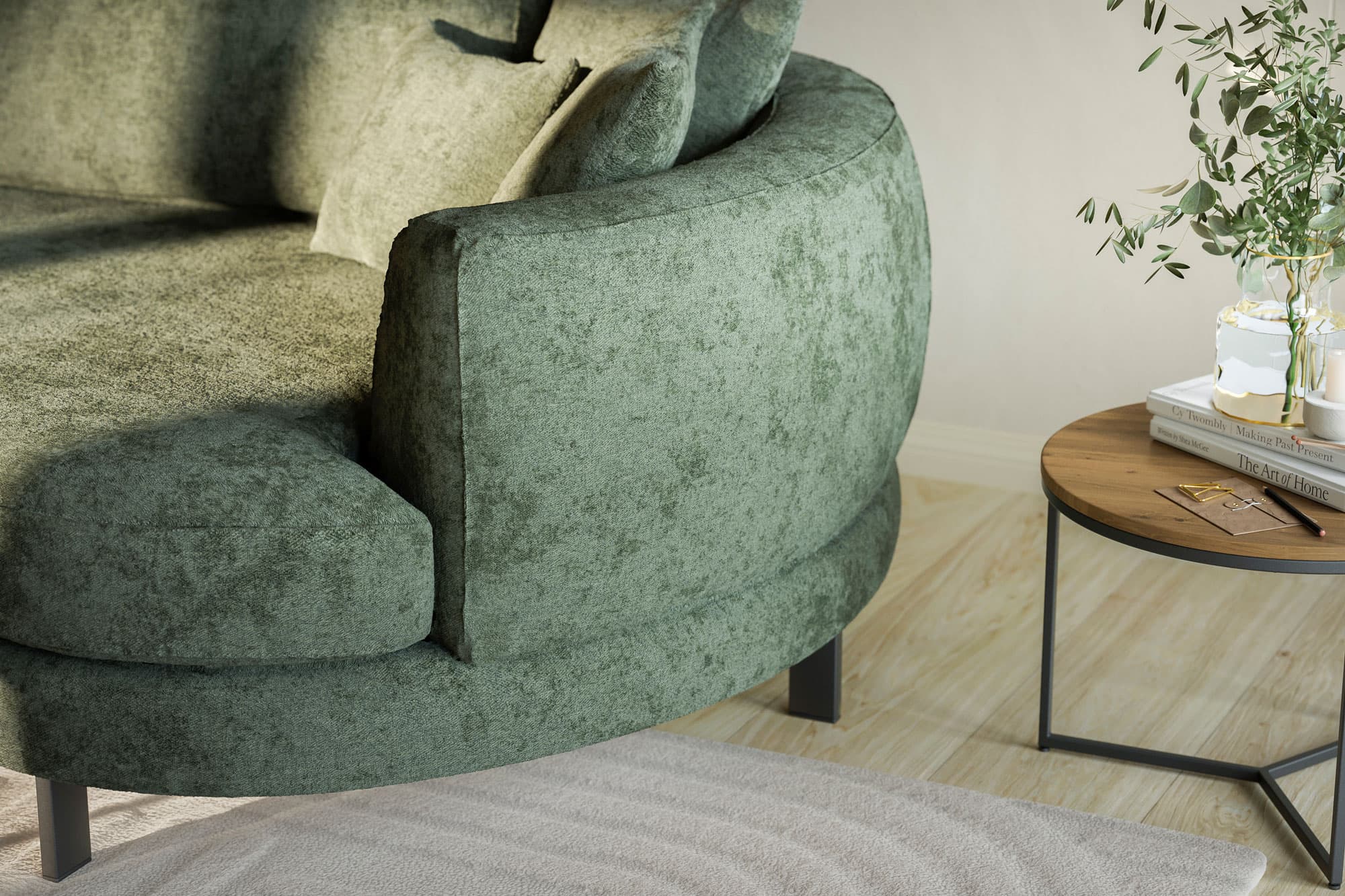Runder, grüner Lounge-Sessel neben einem kleinen Holztisch und einer Pflanze im Hintergrund auf einem hellen Boden.